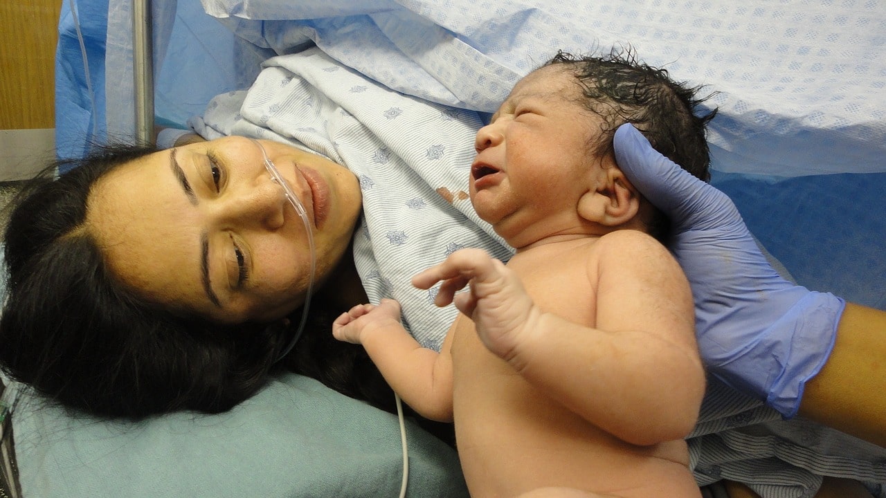 Mother in hospital smiling at her newborn baby